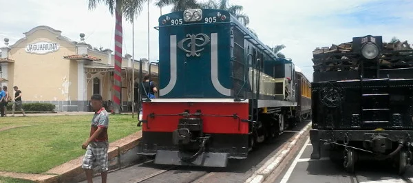 Estação Jaguariúna da VFCJ com locomotiva a diesel e composição com Maria Fumaça e carro contendo madeira para queima sobre trilhos instalados em calçado e asfalto. Foto: ViniRoger.