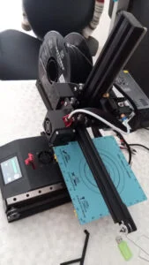 Impressora 3D utilizada, com rolo de filamento preto e fonte ao fundo. Foto: ViniRoger