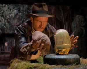 Indy tentando pegar o ídolo sem disparar as armadilhas. Créditos: Disney/Divulgação