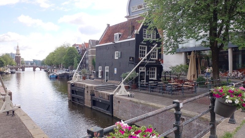 De Sluyswacht (bar em antiga torre do canal que entortou bastante com os anos) e canal Oudeschans com Montelbaanstoren ao fundo (torre de defesa do século 16, outrora parte das muralhas da cidade, com sinos e um relógio adicionado em 1606). Foto: ViniRoger